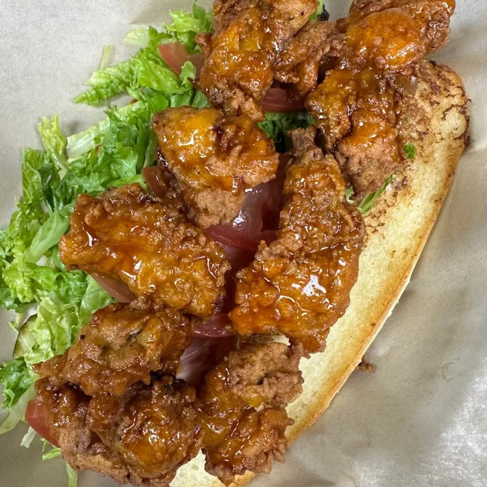 A Georgia Comfort Kitchen fried chicken po'boy with lettuce and tomato on a toasted bun.